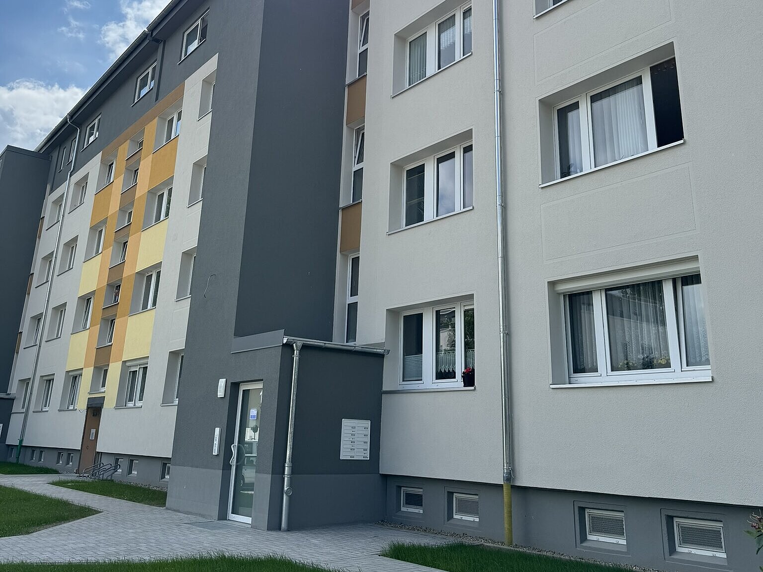Eingangsbereich des durch das Görlitzer Architekturbüro AIP sanierten Wohnblocks auf der Adolph-Kolping-Str. 11-29 in Bautzen, in gelber Farbe 